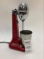 Front angled view of the red Hamilton Beach milkshake maker with stainless steel cup inserted.