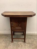 Front view of the solid wood cabinet with closed swivel folding top, showing carved door with key lock.
