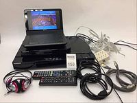 Full view of the lot showing Sony portable player open with video, and Samsung Blu-ray players plus cables and remotes