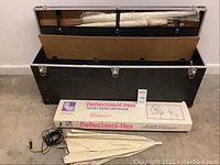 Open black carrying case showing two folded white soft light umbrellas inside the lid compartment and black accessories case below.