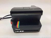 Front view of black Polaroid 600 Land Camera Spirit with rainbow stripe and film slot visible