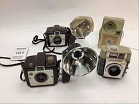Lot of four vintage Kodak cameras including two Brownie Holiday Flash models with side flash attachments, a Brownie Star Meter camera, and a Flash Fun camera. Flash units show some damage.