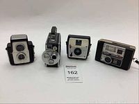 Four vintage cameras including Brownie Starflex, Keystone Magazine 5, Ansco Cadet, and Keystone Everflash 30 shown from front angles on white background.