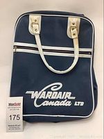Front of the Wardair Canada Ltd blue travel bag with white handles and white printed logo on fabric surface.