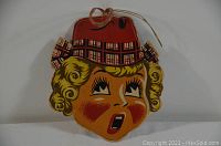 Front view of the cardboard decoration showing the stylized woman's face with blond curls and red hat