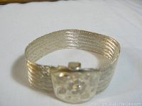 Overall view of the wide sterling silver bracelet showing its ribbed texture and floral clasp design.