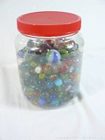 Plastic jar with red lid filled with colorful vintage marbles