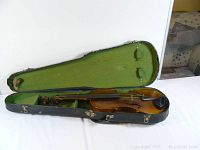 Violin in open hard case showing full length and worn green felt lining