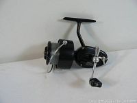 Full view of black vintage Garcia Mitchell 300 fishing reel with fishing line on the spool.