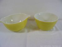Front view of two yellow Pyrex mixing bowls, one with pouring spout and handles, other round