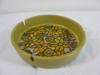 Round ceramic ashtray with mustard yellow outer glaze and intricate multi-colored floral design inside base, shown from top angle.