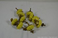 Photo of 8 yellow ceramic drawer knobs with brass hardware and screws on a plain white background.