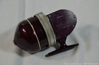 Side view of burgundy South Bend fishing reel with cream trim and handle