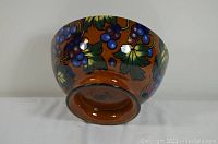 Side and bottom view showing colorful grape and leaf design and manufacturer's mark on base.