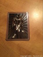 Front view of Randy Moss 1998 Bowman football rookie card in hard plastic sleeve showing player in uniform with number 18 and radiating background.