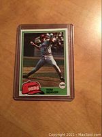 Front of 1981 Topps Tom Seaver Cincinnati Reds baseball card in protective plastic sleeve showing pitching action photo from game.