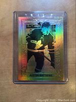 Front of 2018-19 Upper Deck Tim Hortons Auston Matthews Gold Etchings insert hockey card, showing holographic image with player in black Toronto Maple Leafs uniform and detailed etched border.