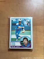 Front view of Dave Stieb 1983 Topps baseball card showing player in pitching pose and headshot, card in protective sleeve on wooden surface.