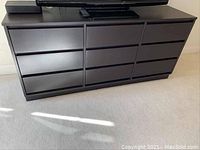 Front view of the dark wood Bassett bedroom bureau showing 12 drawers with recessed handles.