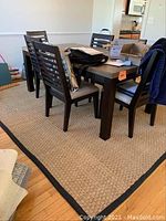 Braided rug underneath dining table and chairs, showing the overall size and placement.