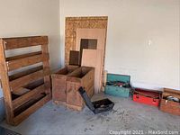 Wide shot showing wooden pallet, two crates, scrap wood panels, and three toolboxes including power craft tool box, red toolbox, and wooden toolbox.