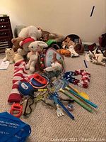 View of assorted holiday decorations, stuffed animals, and beach toys arranged on carpeted floor.
