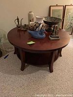 Overall view of the round dark wood coffee table with various decorative items placed on top, showing the table's shape and surface condition.