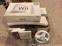 Overview showing boxed Wii console, steering wheel, game cases and grey disc accessories