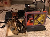 Vintage Bell & Howell TDC Selectron projector, K&B Crystal Radio Kit box, belts, vintage Polaroid cameras, and Addometer visible on floor