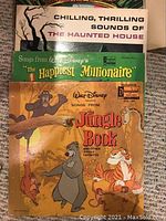 Photo showing vinyl records: The Haunted House, The Happiest Millionaire, The Jungle Book with colorful illustrated covers.
