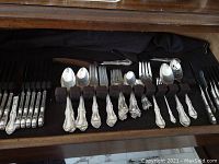 Overview of flatware in storage tray showing assorted forks, spoons and knives.