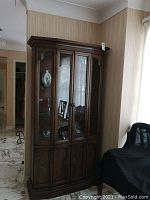 Full front view of the wood display cabinet showing glass shelves and glass doors on the upper section, and closed bottom cupboard doors.