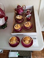 Overview of tea set laid out in box showing cups, saucers, creamer, sugar bowl, teapot