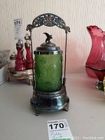 Full view of the pickle cruet showing green embossed glass jar with silver plated holder, floral handle, and bird handle lid. Shows overall condition and size.