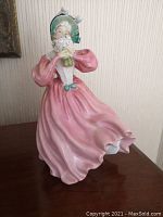 Three-quarter left-front view of figurine, showing face, bouquet, and flowing pink dress.