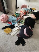 Overview of three hats, gloves, scarves, belts and purses on carpet