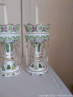 Pair of lusters side by side on a tabletop, each holding a taper candle