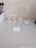 Four-piece Swarovski set on table: three crystal candle sticks with metal spikes and one swan figurine.