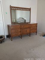 Front and full view of wood dresser with attached mirror and glazed stone top on carpeted floor