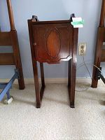 Full view of wooden smoking stand showing front with cabinet door and legs.