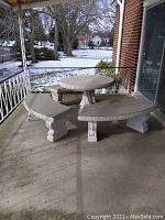 Overview of round table and three curved benches on covered porch