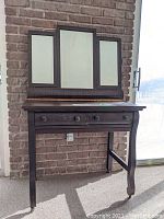 Front view of antique wooden dressing table with 3-panel mirror mounted behind it