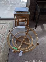 Overview of round coffee table with glass top, nesting tables stacked behind, and lap tray on top