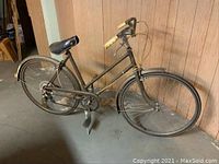 Left side view of the bicycle showing step-through frame, leather saddle, and front wheel.