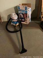 Full view of the compact Shop Vac All Around EZ wet/dry vacuum with hose attached and original box in background.