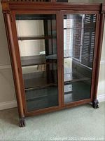 Front view of bookcase showing both glass doors, interior shelves and claw feet