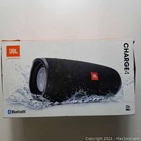 Box of JBL Charge 4 speaker showing waterproof capability and branding on white packaging.
