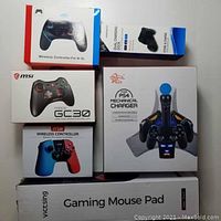 Photo showing all boxed items: MSI Force GC30 wireless controller, JYSW wireless controller, KJH PS4 mechanical charger, Beboncol dual charging dock, Victsing gaming mouse pad.