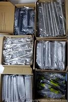 View of six boxes containing various packaged cabinet handles in black and silver finish.