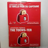 Box of Jonathan Toews toasted themed toaster called Le Grille-Pain Du Capitaine and The Toews-ter, in red color with images of toaster and toasted bread with face of Jonathan Toews.